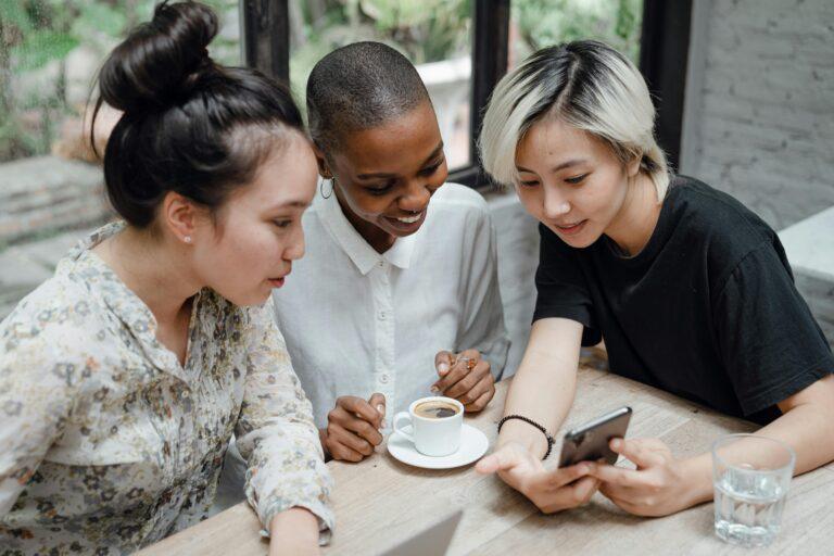 three women are looking at mobile phone screen